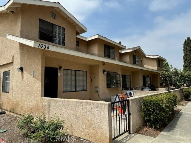 1034 E 6th St Unit 102, Ontario, CA 91764 - back of house with stucco siding, a fenced front yard, and a gate