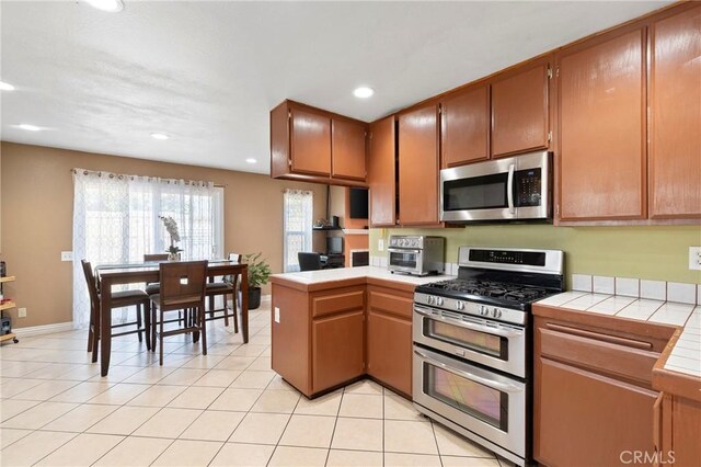 1257 N Brookhurst St, Anaheim, CA 92801 - kitchen with appliances with stainless steel finishes, tile counters, a peninsula, recessed lighting, and light tile patterned flooring