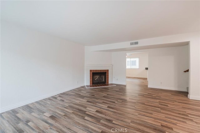 2254 Gaviota Ave Unit 11, Signal Hill, CA 90755 - unfurnished living room featuring wood finished floors, a brick fireplace, and baseboards