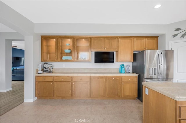 3822 Jupiter Ave, Lompoc, CA 93436 - kitchen with brown cabinetry, stainless steel fridge, glass insert cabinets, light tile patterned floors, and recessed lighting