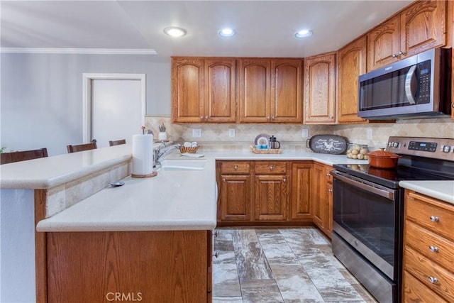 64 Seacrest Ct, Long Beach, CA 90803 - kitchen featuring appliances with stainless steel finishes, brown cabinets, a peninsula, light countertops, and ornamental molding