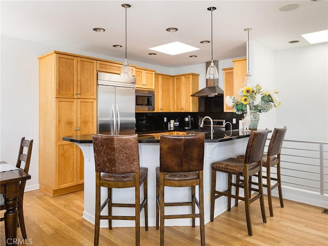 209 41st, Manhattan Beach, CA 90266 - kitchen featuring built in appliances, a skylight, a peninsula, light wood-style flooring, and tasteful backsplash