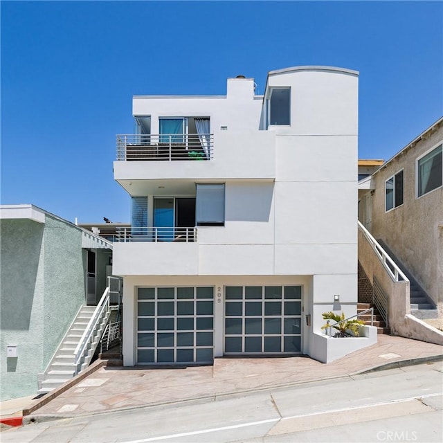 209 41st, Manhattan Beach, CA 90266 - rear view of house with stairs, a balcony, an attached garage, stucco siding, and driveway