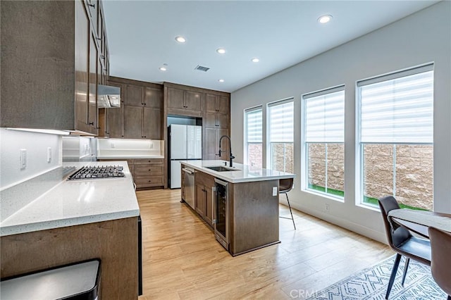 20754 W Bur Oak Cir, Porter Ranch, CA 91326 - kitchen with appliances with stainless steel finishes, light wood-style floors, beverage cooler, recessed lighting, and a kitchen breakfast bar