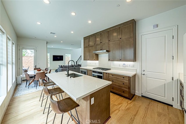 20754 W Bur Oak Cir, Porter Ranch, CA 91326 - kitchen featuring light wood-style floors, an island with sink, a breakfast bar area, plenty of natural light, and recessed lighting