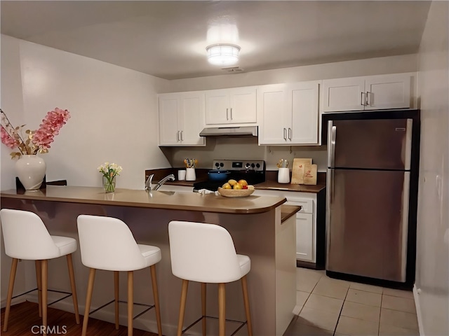 5414 Newcastle Ave Unit 7, Encino, CA 91316 - kitchen featuring stainless steel appliances, under cabinet range hood, white cabinetry, and a breakfast bar area
