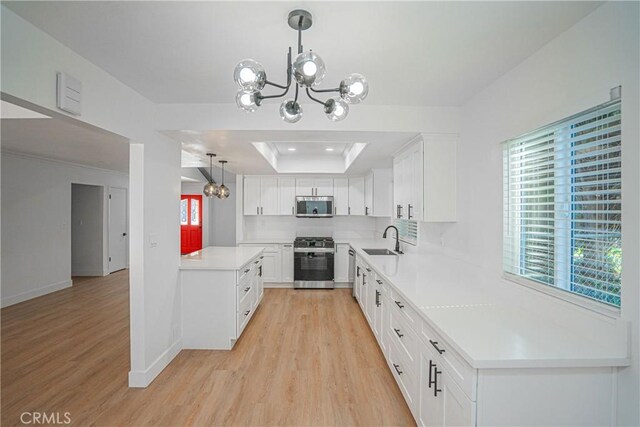 18259 Midbury St, Brea, CA 92821 - kitchen featuring appliances with stainless steel finishes, a chandelier, a tray ceiling, and light wood-style floors