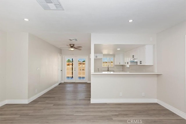 35010 Cedar Rd, Barstow, CA 92311 - kitchen featuring under cabinet range hood, white cabinets, light countertops, light wood-style floors, and recessed lighting