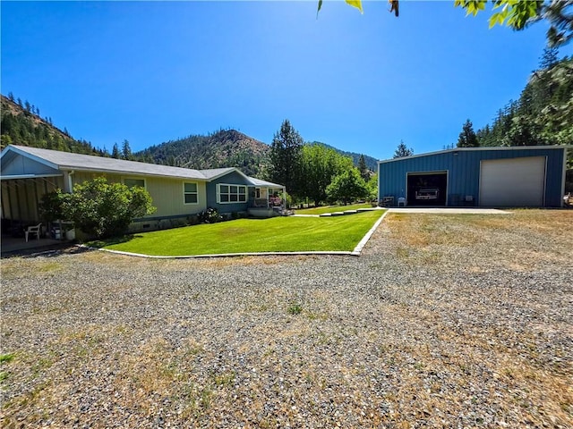 38727 State Highway 96, Klamath River, CA 96050 - view of green lawn with a garage, a mountain view, gravel driveway, and an outdoor structure