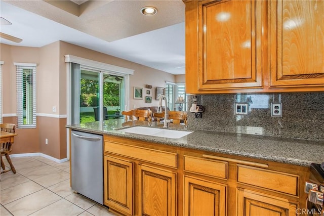 100 Waters Ct, Redlands, CA 92374 - kitchen featuring stainless steel dishwasher, a sink, brown cabinetry, baseboards, and decorative backsplash