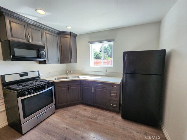 10450 Balboa Blvd, Granada Hills, CA 91344 - kitchen with black appliances, a sink, light wood-type flooring, light countertops, and dark brown cabinets