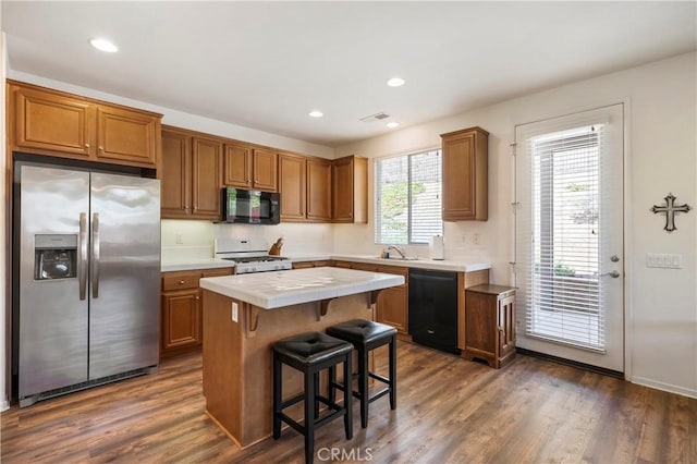 197 Inkster Way, Hemet, CA 92545 - kitchen featuring black appliances, tile countertops, a kitchen island, brown cabinets, and a breakfast bar area