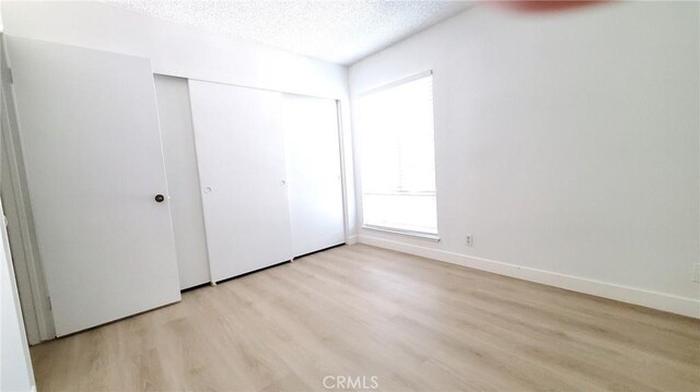 17070 Colima Rd Unit 284, Hacienda Heights, CA 91745 - unfurnished bedroom with light wood finished floors, a textured ceiling, a closet, and baseboards