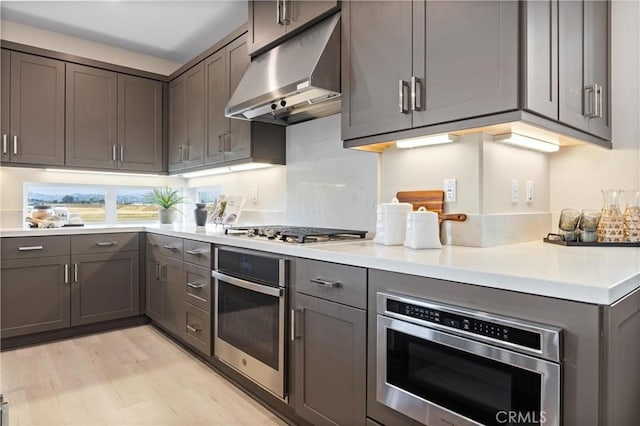 225 Waypoint, Tustin, CA 92782 - kitchen with appliances with stainless steel finishes, under cabinet range hood, light countertops, light wood finished floors, and gray cabinets