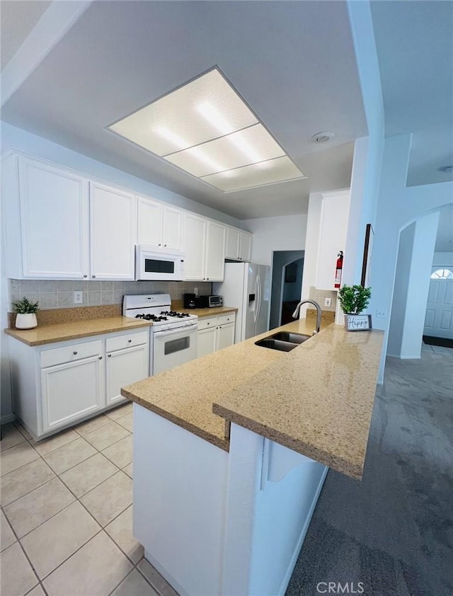 12390 San Dimas St, Victorville, CA 92392 - kitchen featuring white appliances, a sink, white cabinets, and a peninsula
