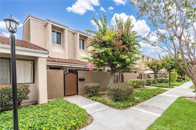 46 Lincoln Ct, Buena Park, CA 90620 - view of property featuring a gate, a fenced front yard, stucco siding, and a tile roof