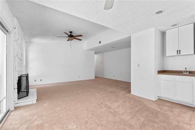 30369 Colina Verde St, Temecula, CA 92592 - unfurnished living room featuring a ceiling fan, light carpet, a textured ceiling, a high end fireplace, and a sink