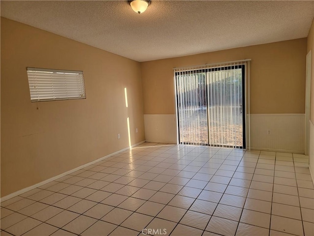 733 Piccadilly, Hemet, CA 92544 - spare room with wainscoting, a textured ceiling, and light tile patterned floors