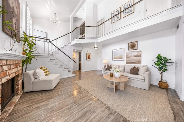 1665 Bridgeport, West Covina, CA 91791 - living room with stairway, wood finished floors, a brick fireplace, a high ceiling, and a chandelier