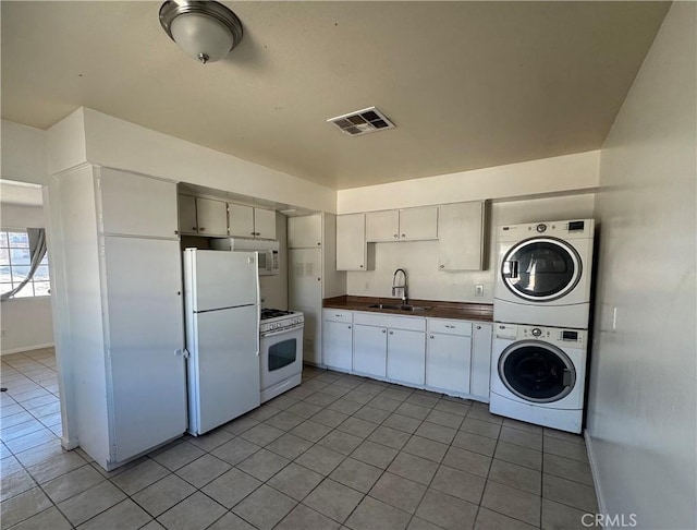 255 W Grace St, Barstow, CA 92311 - kitchen with white appliances, stacked washer / dryer, light tile patterned flooring, and white cabinets