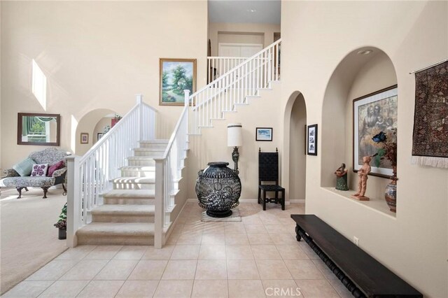 3262 Bluebird Cir, Simi Valley, CA 93063 - staircase with arched walkways, a high ceiling, tile patterned flooring, carpet flooring, and plenty of natural light