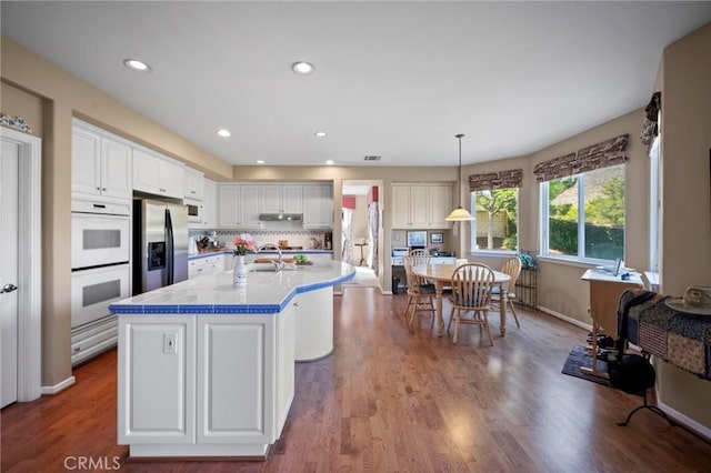 3262 Bluebird Cir, Simi Valley, CA 93063 - kitchen featuring white double oven, stainless steel refrigerator with ice dispenser, white cabinets, light countertops, and wood finished floors