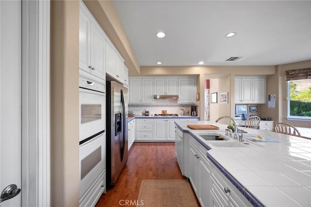 3262 Bluebird Cir, Simi Valley, CA 93063 - kitchen featuring appliances with stainless steel finishes, under cabinet range hood, white cabinets, recessed lighting, and tile countertops