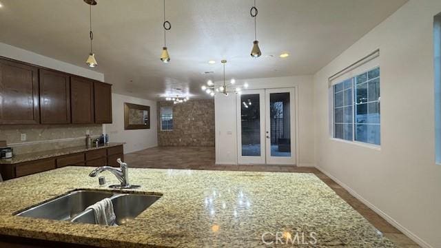 345 W Saint Andrews St, Ontario, CA 91762 - kitchen with pendant lighting, light stone counters, a center island with sink, dark brown cabinetry, and french doors