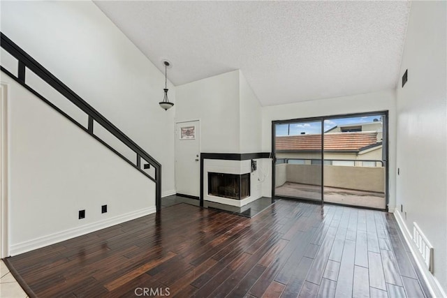 13115 Le Parc Unit 40, Chino Hills, CA 91709 - unfurnished living room with wood finished floors, a multi sided fireplace, a textured ceiling, baseboards, and stairway