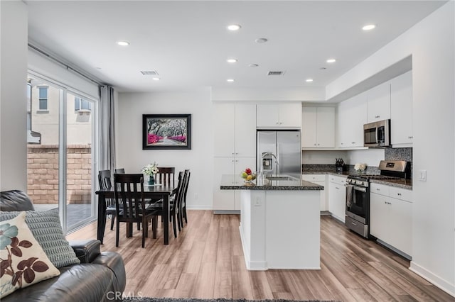 7452 Desert Holly St, Chino, CA 91708 - kitchen with stainless steel appliances, light wood finished floors, a center island with sink, white cabinets, and recessed lighting