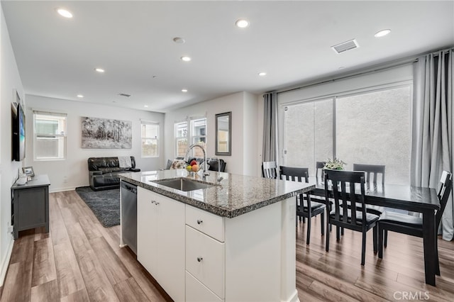 7452 Desert Holly St, Chino, CA 91708 - kitchen featuring a sink, dishwasher, light wood-style flooring, dark stone counters, and a kitchen island with sink