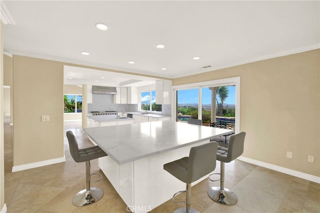 3313 Cabo Ct, Carlsbad, CA 92009 - kitchen with white cabinetry, a breakfast bar area, ornamental molding, recessed lighting, and a center island