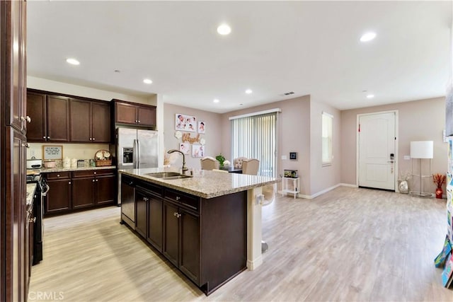 6045 Lyon St, Chino, CA 91710 - kitchen with light wood-style floors, an island with sink, dark brown cabinetry, light stone counters, and recessed lighting