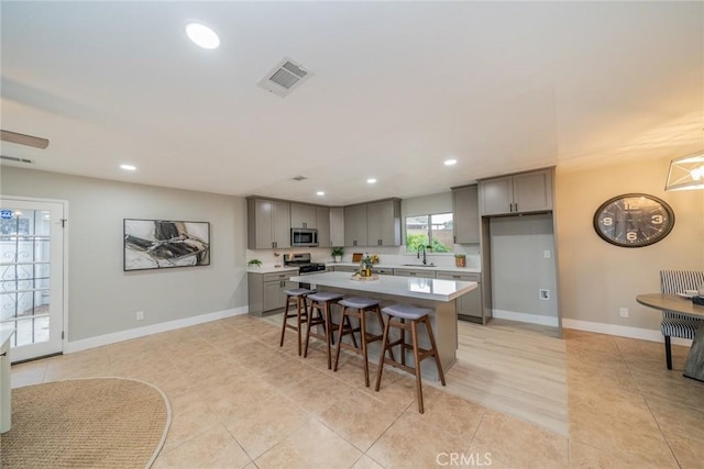 6367 Willow Ave, Rialto, CA 92377 - kitchen with gray cabinets, stainless steel microwave, recessed lighting, a kitchen island, and light countertops