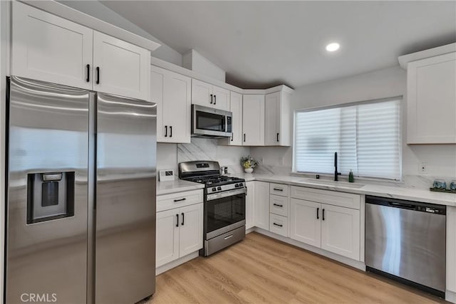 16409 Barbee St, Fontana, CA 92336 - kitchen featuring stainless steel appliances, white cabinetry, light stone countertops, tasteful backsplash, and vaulted ceiling