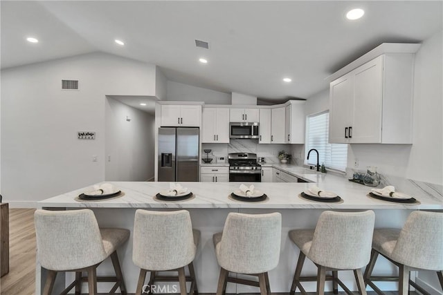 16409 Barbee St, Fontana, CA 92336 - kitchen with appliances with stainless steel finishes, a peninsula, vaulted ceiling, white cabinets, and recessed lighting