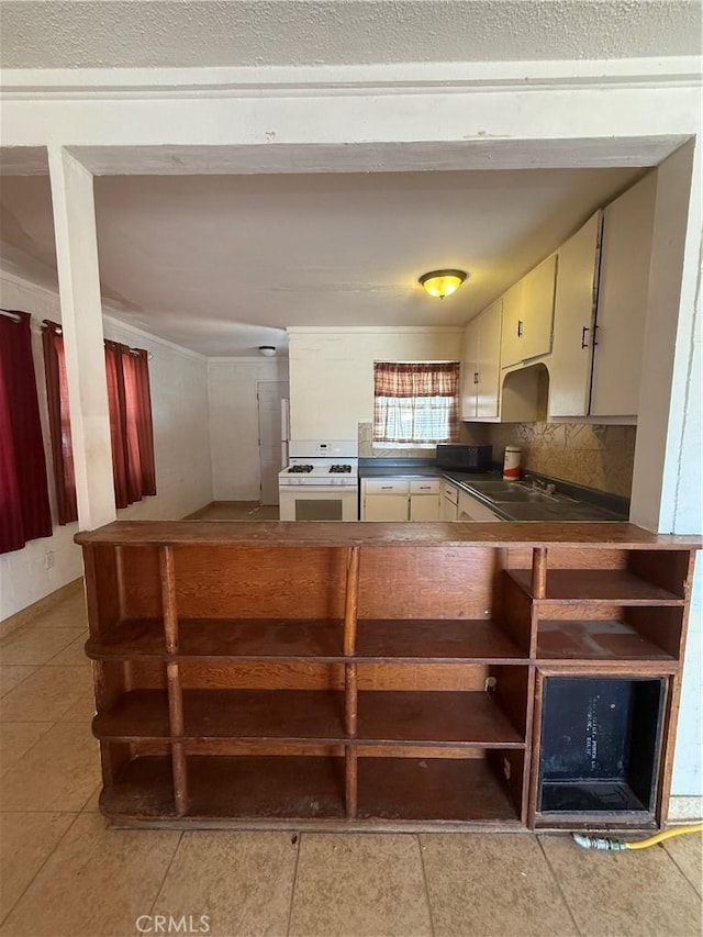 6733 Tamarisk Ave Unit 29, Palms, CA 92277 - kitchen with white range with gas stovetop, dark countertops, light tile patterned flooring, and tasteful backsplash