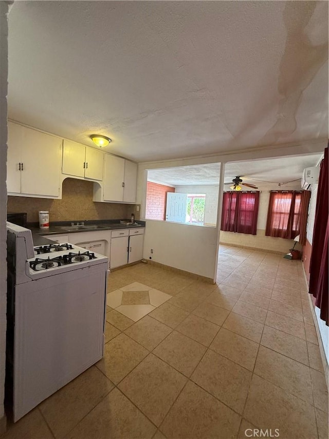 6733 Tamarisk Ave Unit 29, Palms, CA 92277 - kitchen with white range with gas stovetop, dark countertops, a ceiling fan, and white cabinets