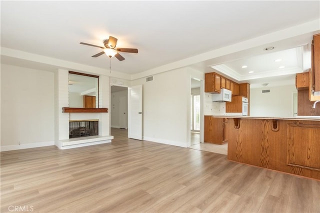 24912 Delos Ave, Mission Viejo, CA 92691 - unfurnished living room featuring a ceiling fan, light wood-style floors, a fireplace, a raised ceiling, and recessed lighting
