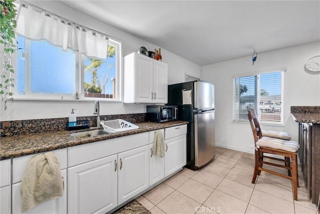 155 N Acacia Ave, Rialto, CA 92376 - kitchen with a sink, freestanding refrigerator, black microwave, white cabinetry, and light tile patterned flooring