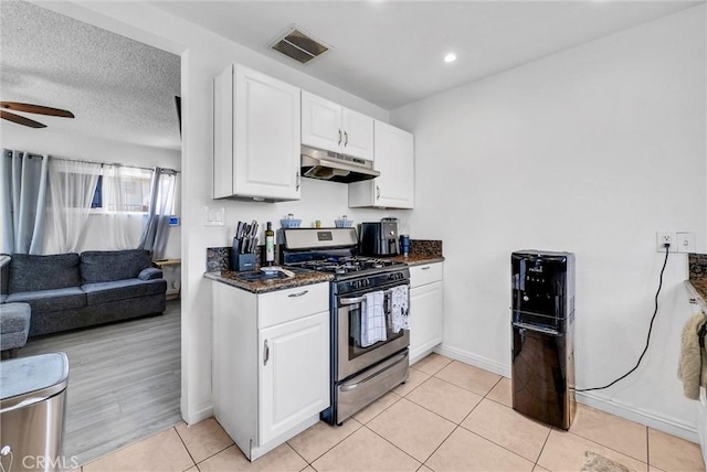 155 N Acacia Ave, Rialto, CA 92376 - kitchen with gas range, under cabinet range hood, white cabinets, open floor plan, and a ceiling fan
