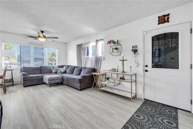 155 N Acacia Ave, Rialto, CA 92376 - living area with light wood finished floors, a textured ceiling, a ceiling fan, and an AC wall unit