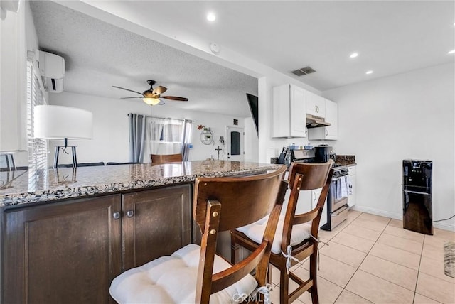 155 N Acacia Ave, Rialto, CA 92376 - kitchen with range with gas stovetop, under cabinet range hood, an AC wall unit, stone countertops, and white cabinets