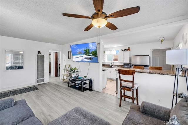 155 N Acacia Ave, Rialto, CA 92376 - living area featuring a heating unit, a ceiling fan, a textured ceiling, baseboards, and light wood finished floors