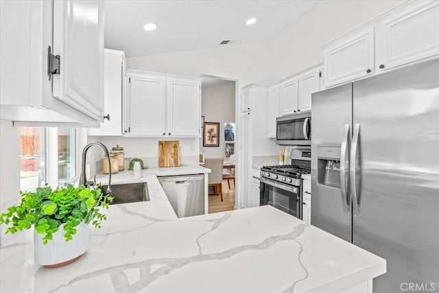 3176 Landmark Ct, Riverside, CA 92503 - kitchen featuring appliances with stainless steel finishes, white cabinetry, light stone counters, a peninsula, and lofted ceiling