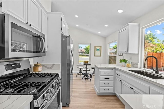 3176 Landmark Ct, Riverside, CA 92503 - kitchen featuring stainless steel appliances, white cabinets, light wood-style flooring, recessed lighting, and vaulted ceiling