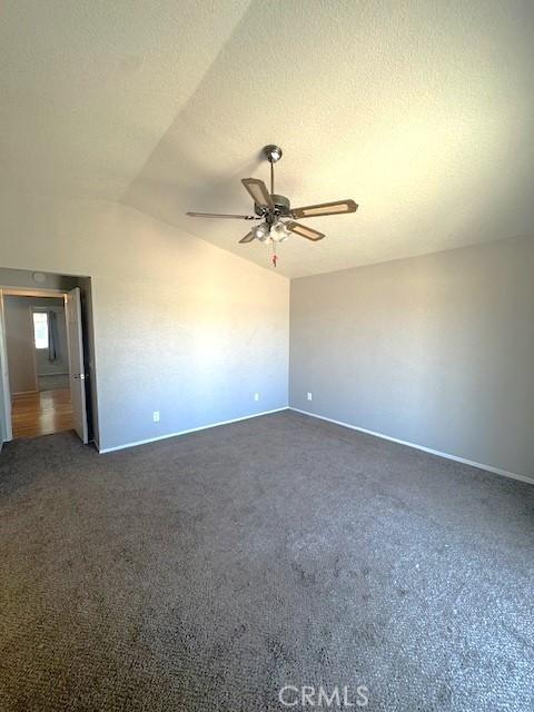 20826 Otowi Rd, Apple Valley, CA 92308 - spare room featuring a ceiling fan, lofted ceiling, baseboards, and dark colored carpet