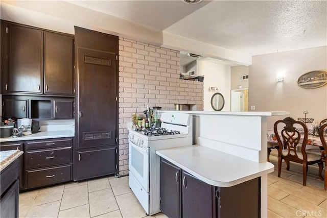 1126 W W Ave H6, Lancaster, CA 93534 - kitchen with white range with gas cooktop, light countertops, light tile patterned flooring, dark brown cabinetry, and a textured ceiling