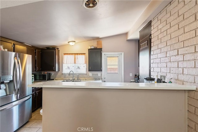 1126 W W Ave H6, Lancaster, CA 93534 - kitchen featuring stainless steel appliances, light countertops, light tile patterned floors, a peninsula, and brick wall