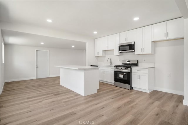 1151 Grand Ave, Colton, CA 92324 - kitchen with stainless steel appliances, light countertops, white cabinets, light wood finished floors, and a kitchen island